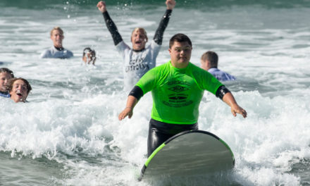 (OC Register) Edison High School surf team members teach kids with disabilities how to ride waves